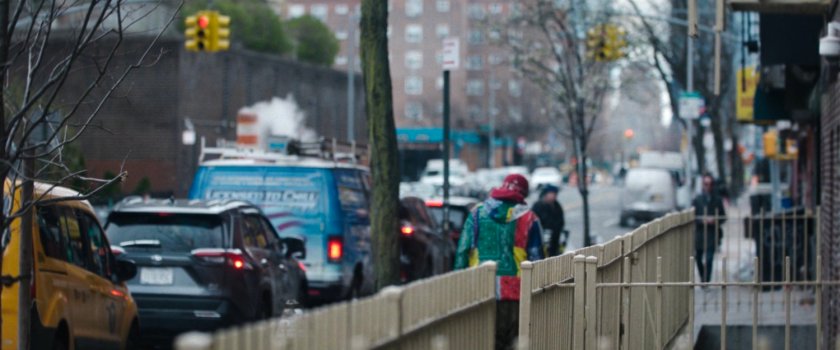 Interstitial: city street seen from behind fence.