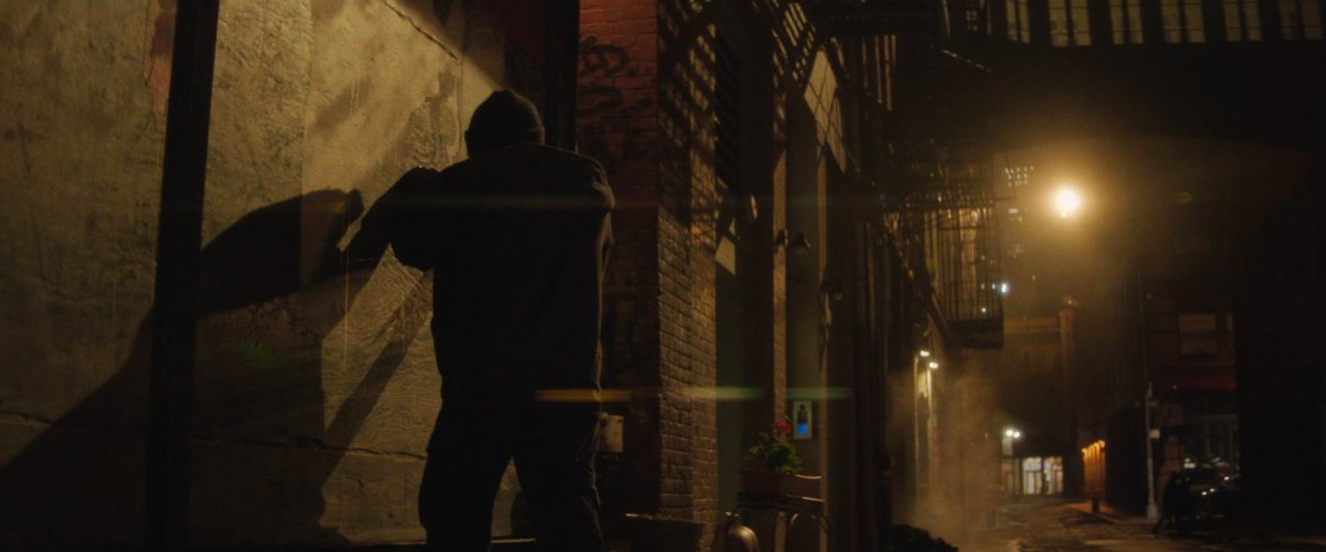 Muse working on a mural in a dark alley.