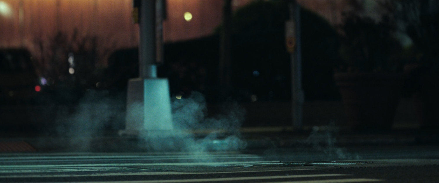 Interstitial: nighttime crosswalk with steaming manhole.