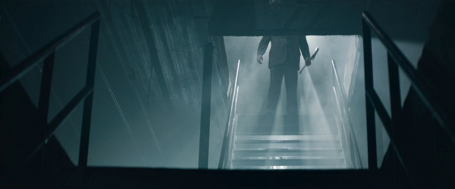 Fisk descending stairs into his "dungeon" with an ax.