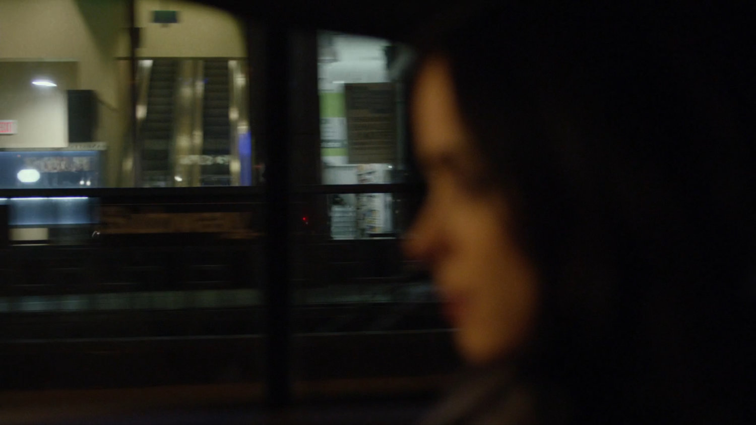 View of storefronts from taxi at night.