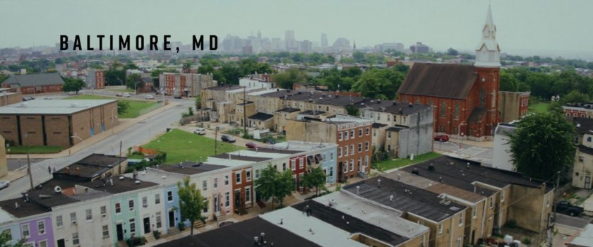 Aerial of Baltimore buildings and street. Text: Baltimore, MD.