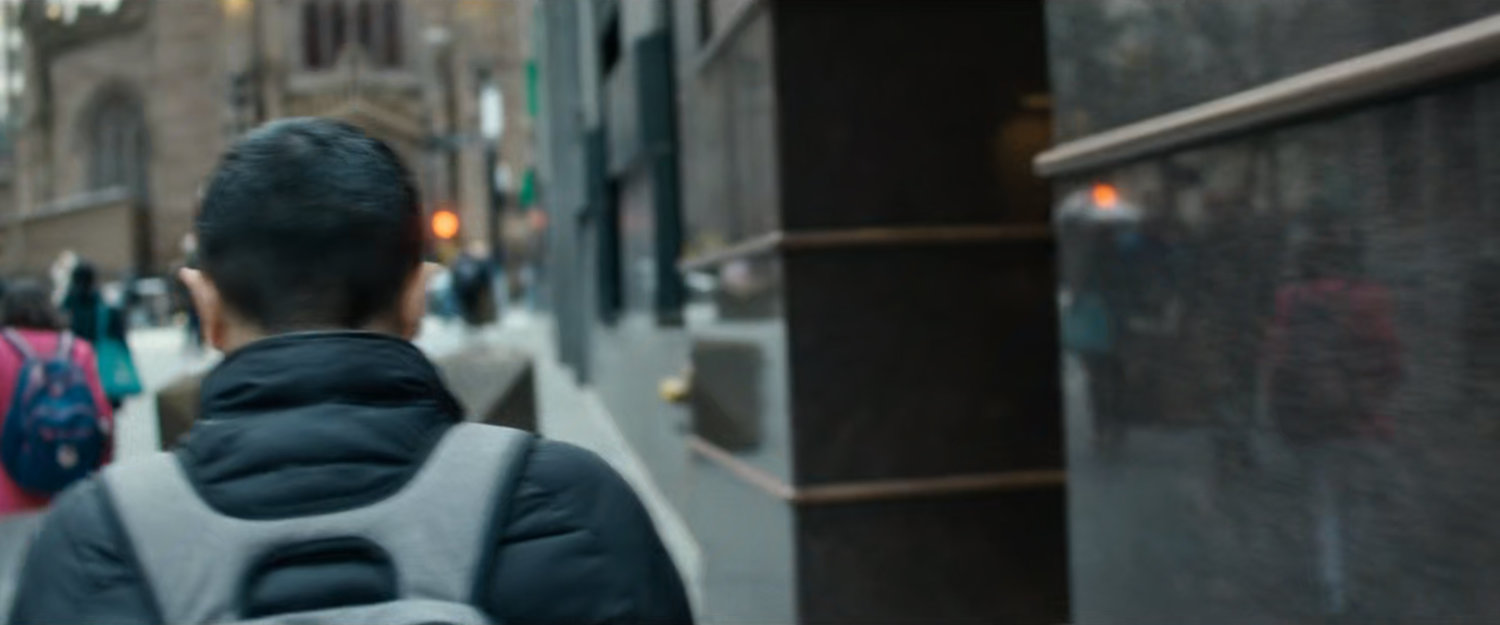 Interstitial: man with backpack walking along sidewalk.