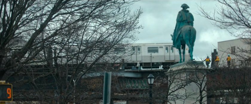 Interstitial: Train on elevated track with workers, statue of man on horse.