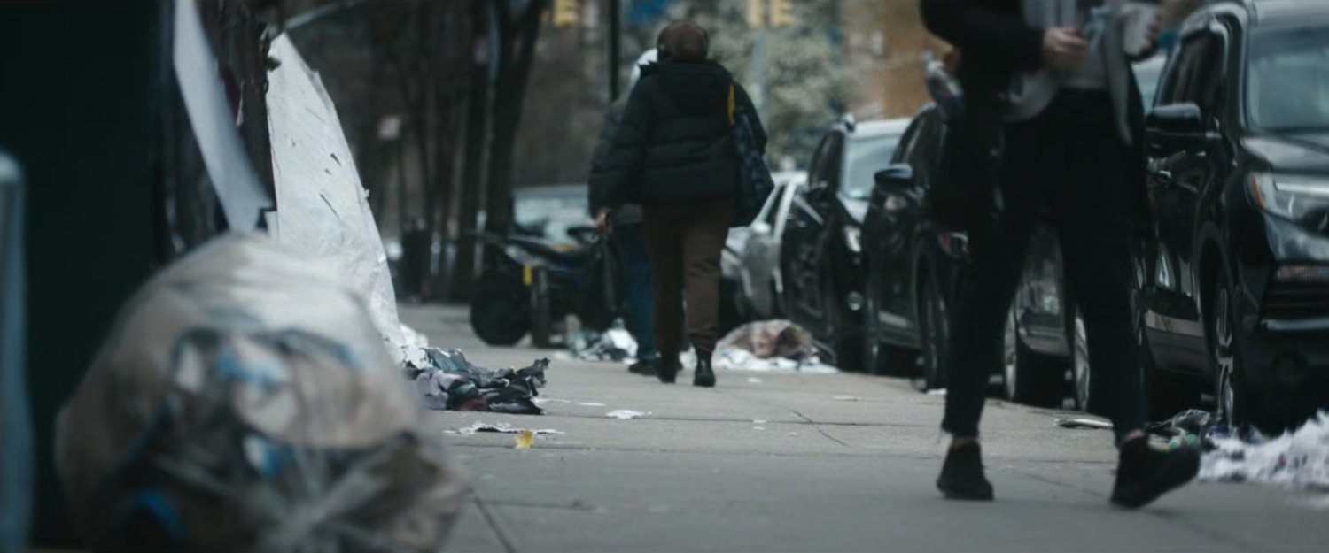 Interstitial: people walking along sidewalk with trash bags.