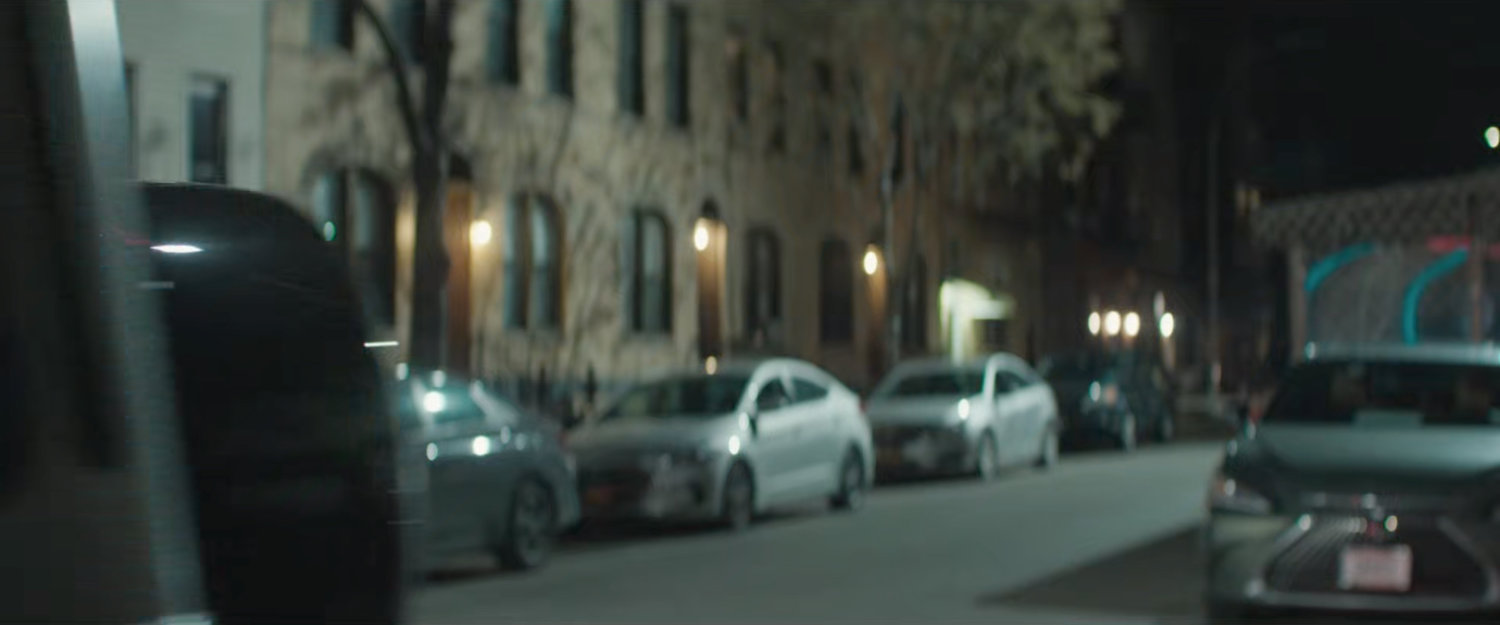 Luca driving away outside some buildings.
