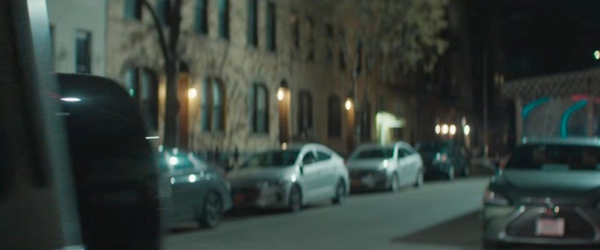 Luca driving away outside some buildings.