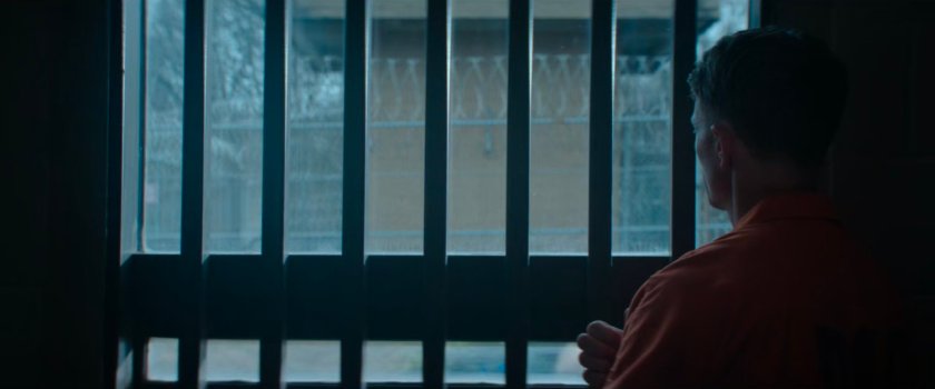 Ben Poindexter looking out window at guard tower at Ryker's Island Penitentiary.