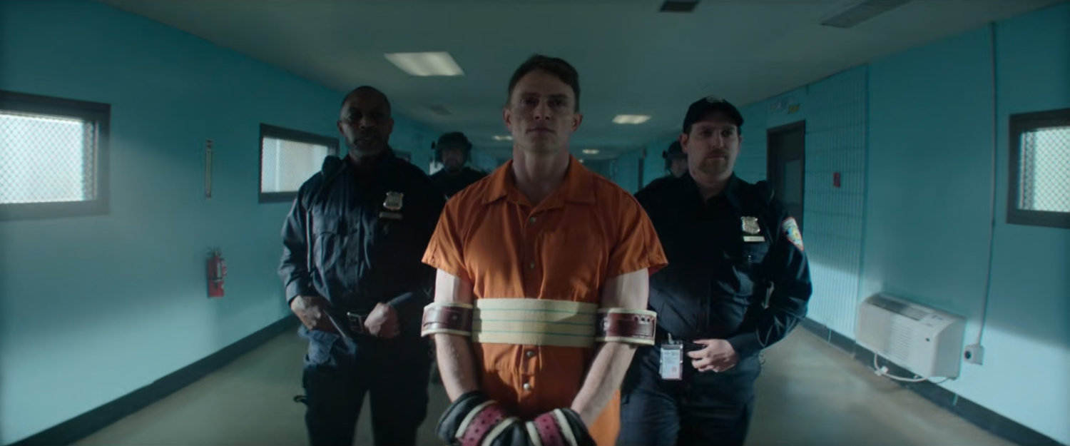 Guards walk Dex down hallway in Ryker's Island Penitentiary.