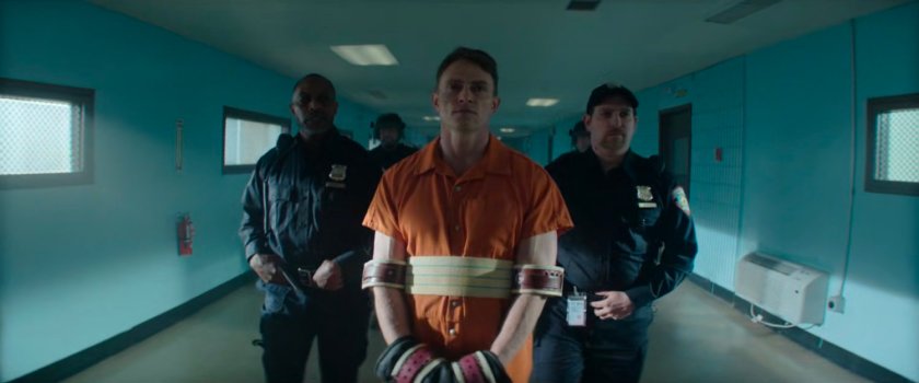 Guards walk Dex down hallway in Ryker's Island Penitentiary.