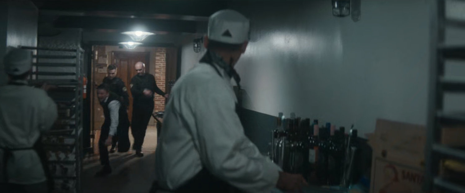 Police officers toss a reporter into the kitchen at the Black & White Ball.