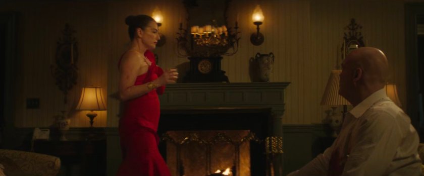 Vanessa standing next to the fireplace in their bedroom as Fisk watches her.