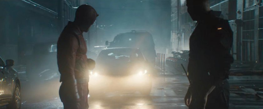 Frank and Matt standing in front of car with headlights on outside Matt's apartment building.