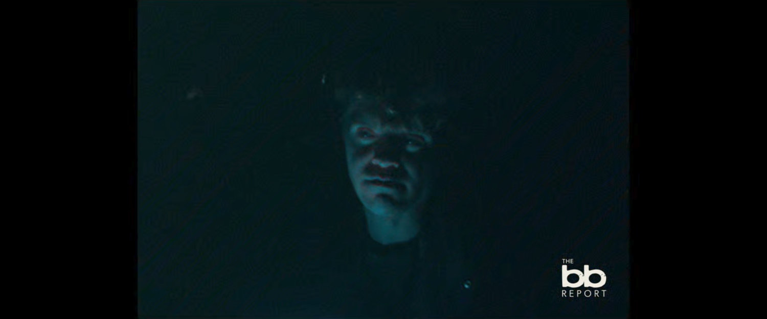 BB Report: Interview with man in dark lit by cell phone light.