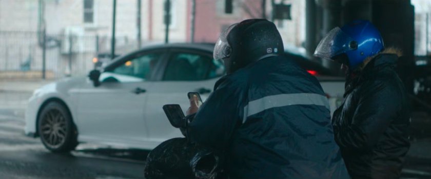 Interstitial: two motorcycle riders under overpass looking at phone.