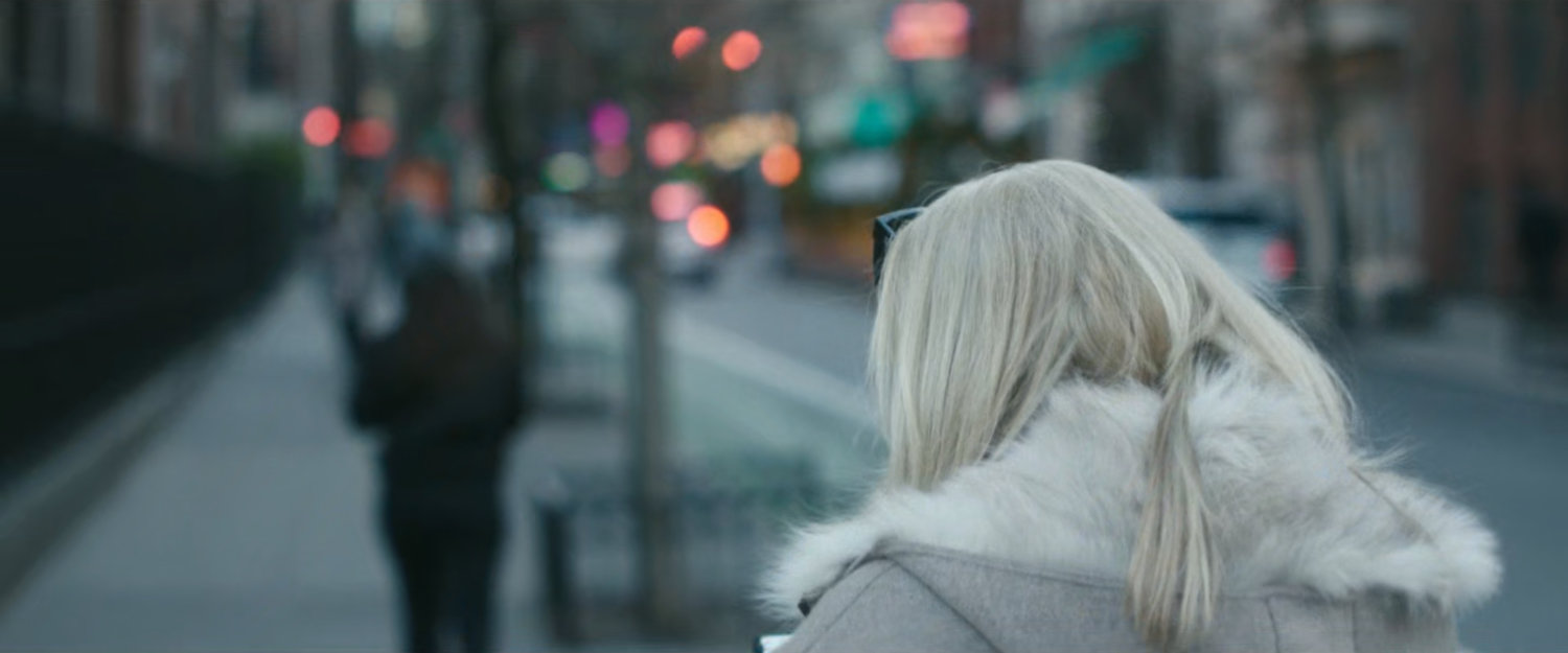 Interstitial: blonde woman walking along sidewalk.