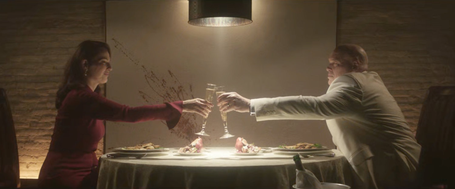 Fisk and Vanessa tasting each other at a dining table in his dungeon.