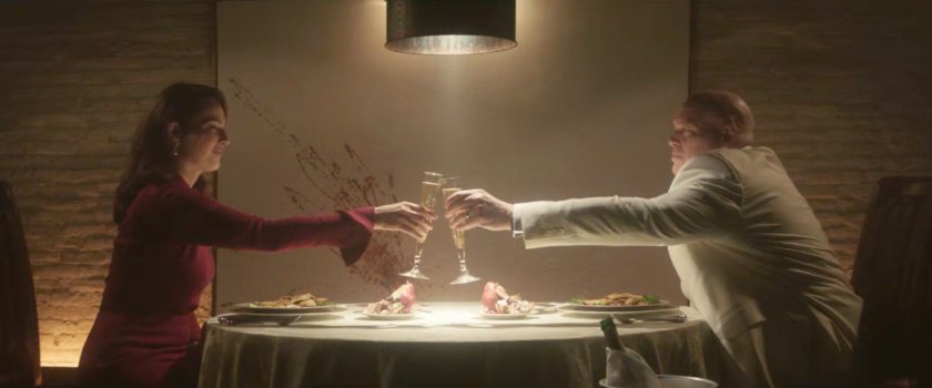 Fisk and Vanessa tasting each other at a dining table in his dungeon.