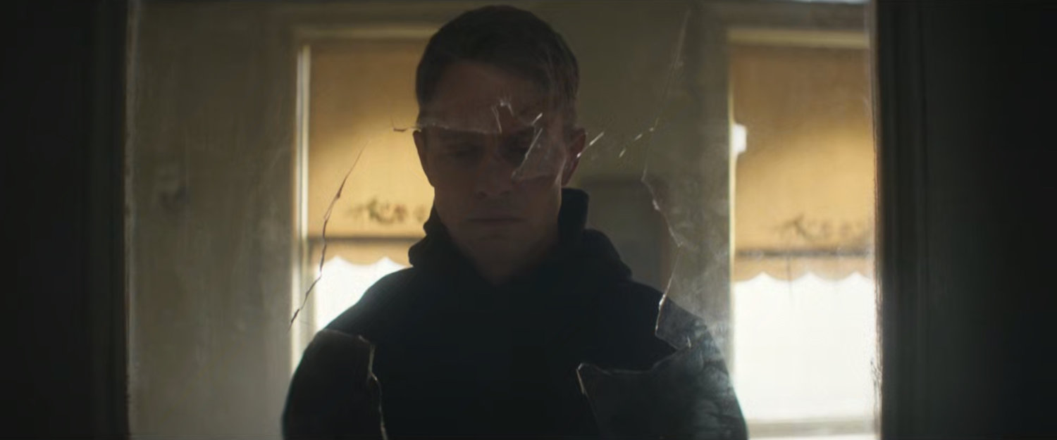 Dex looking through a broken window in an apartment.