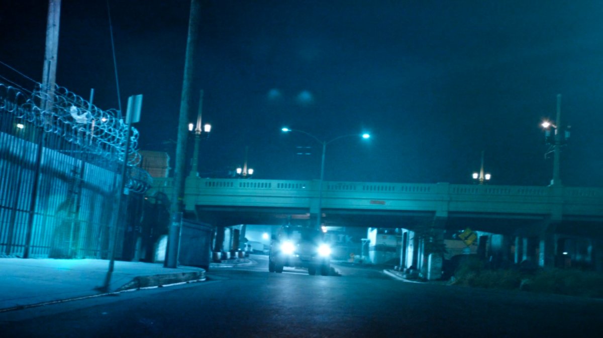A Watchdog pickup drive along a night street under a bridge.