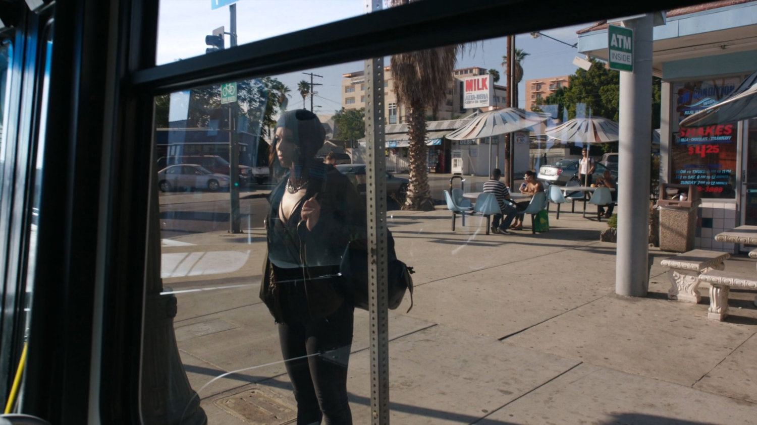 Daisy waiting at a bus stop outside Jim's Burgers.