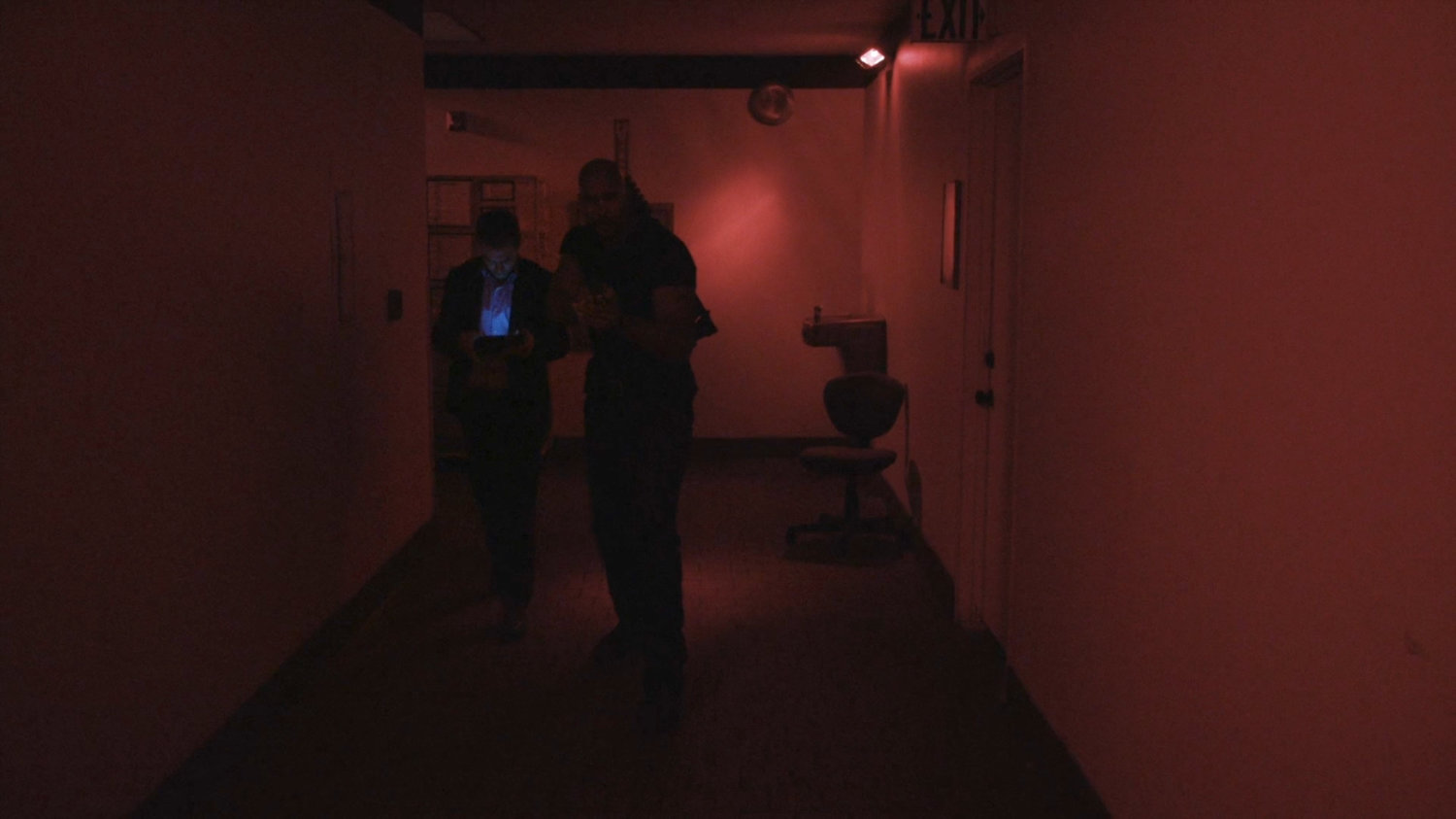Fitz and Mack in red lit interior hallway in Momentum Labs.