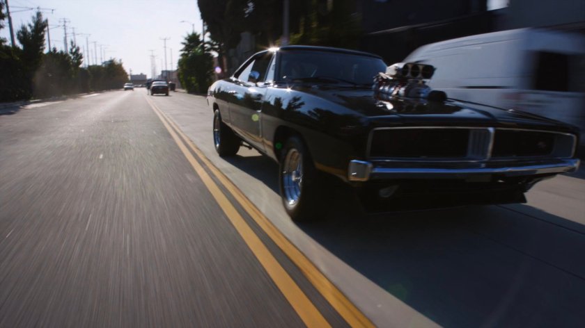 Black charger driving on street.