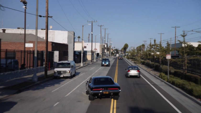Black charger driving on street.