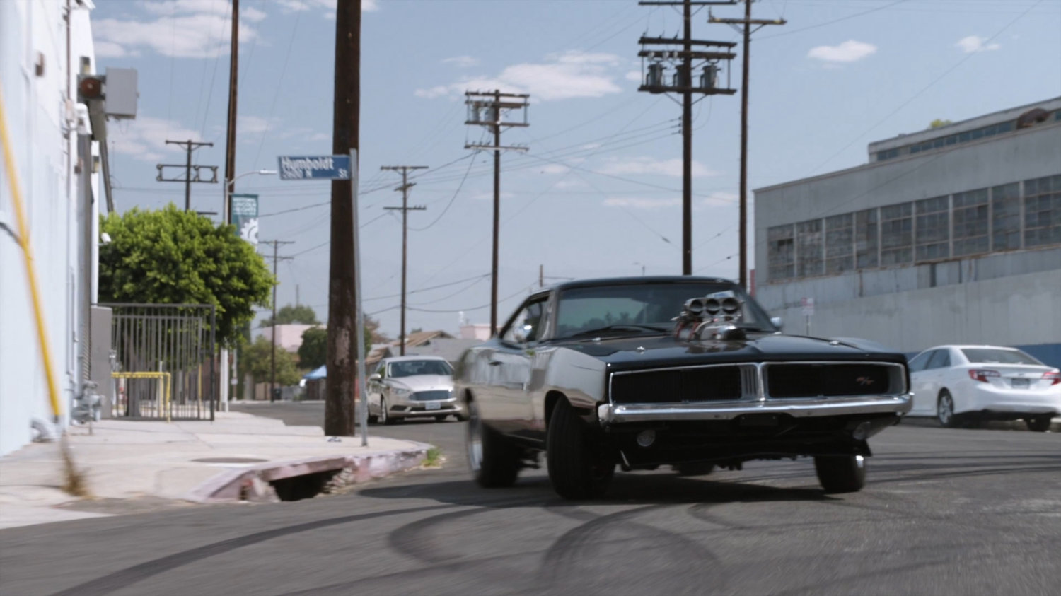 Lola chasing black Charger along street.
