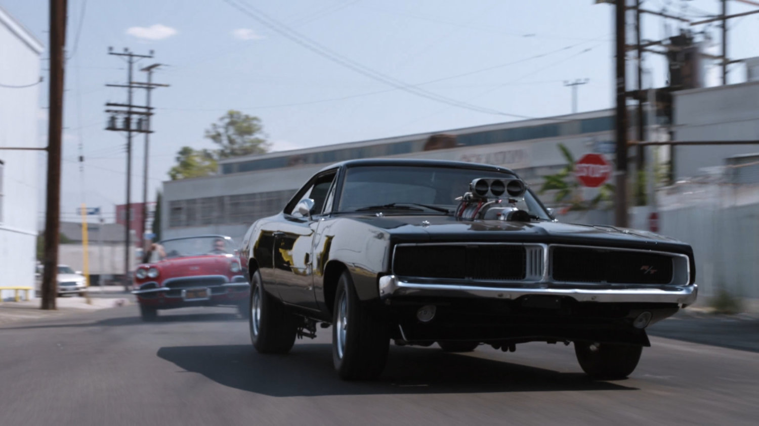 Lola chasing black Charger along street.