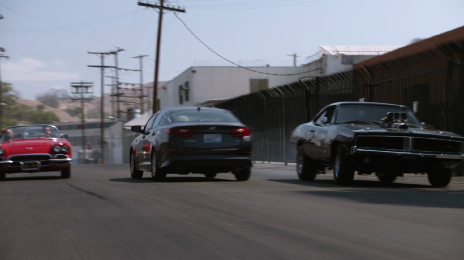Lola chasing black Charger along street.