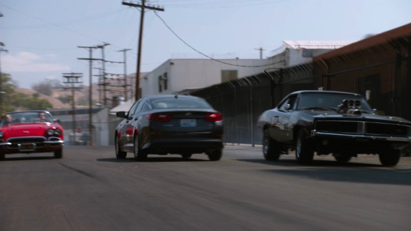Lola chasing black Charger along street.