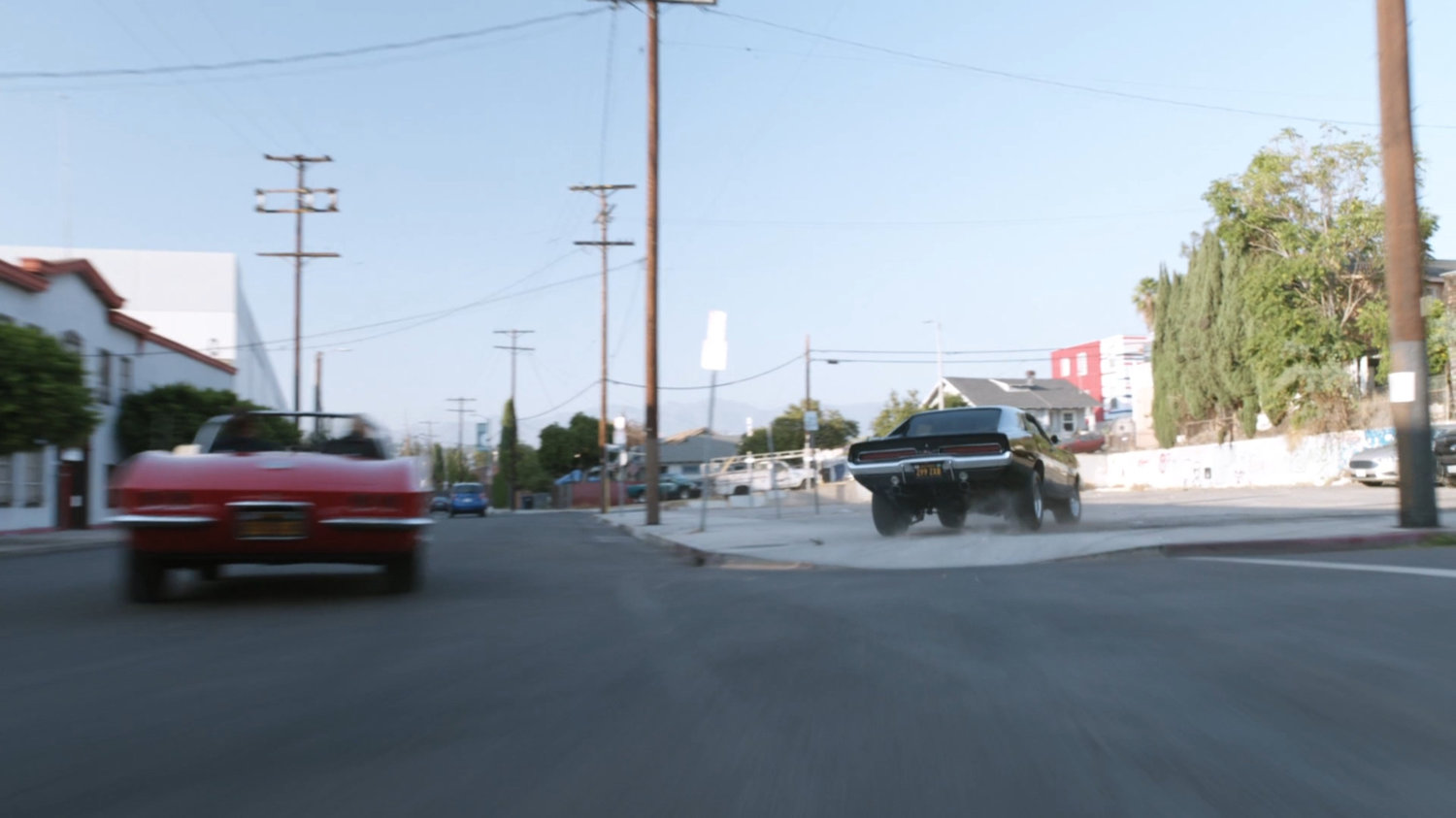 Lola chasing black Charger along street.