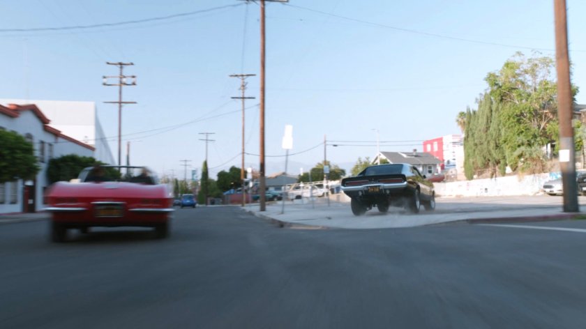 Lola chasing black Charger along street.