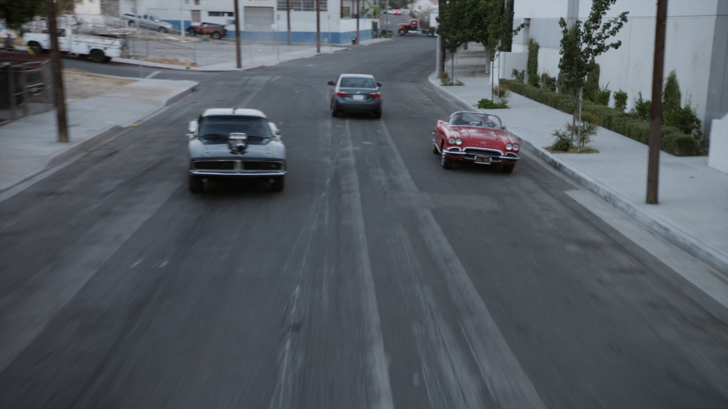 Lola chasing black Charger along street.