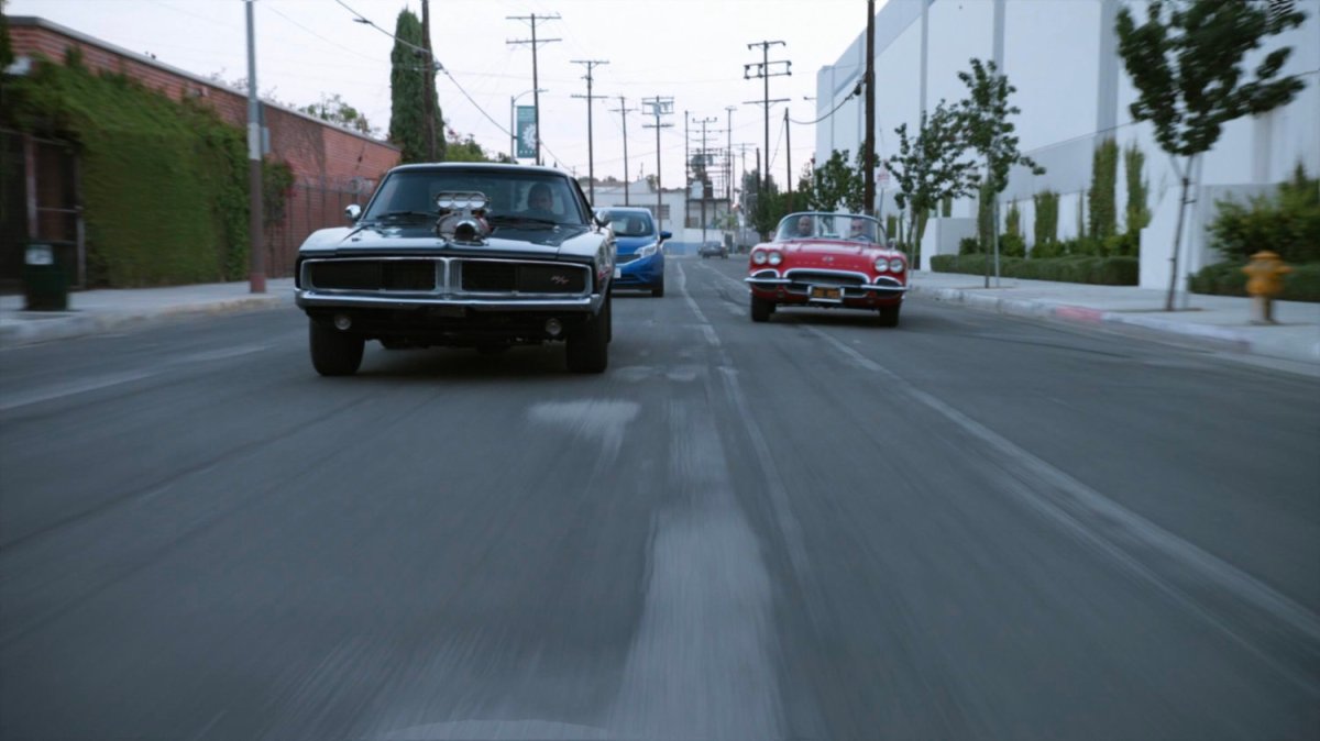 Lola chasing black Charger along street.
