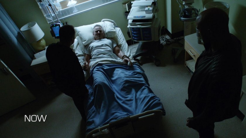 Coulson and Mack standing over Joseph Bauer in his hospital room. Text: Now.