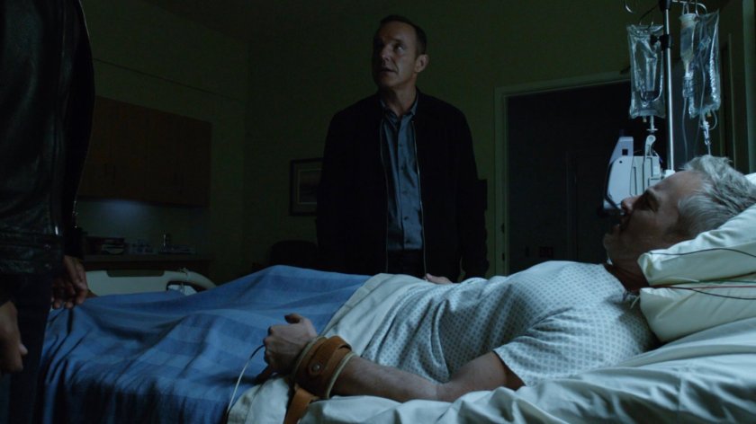 Coulson and Mack standing over Joseph Bauer in his hospital room.