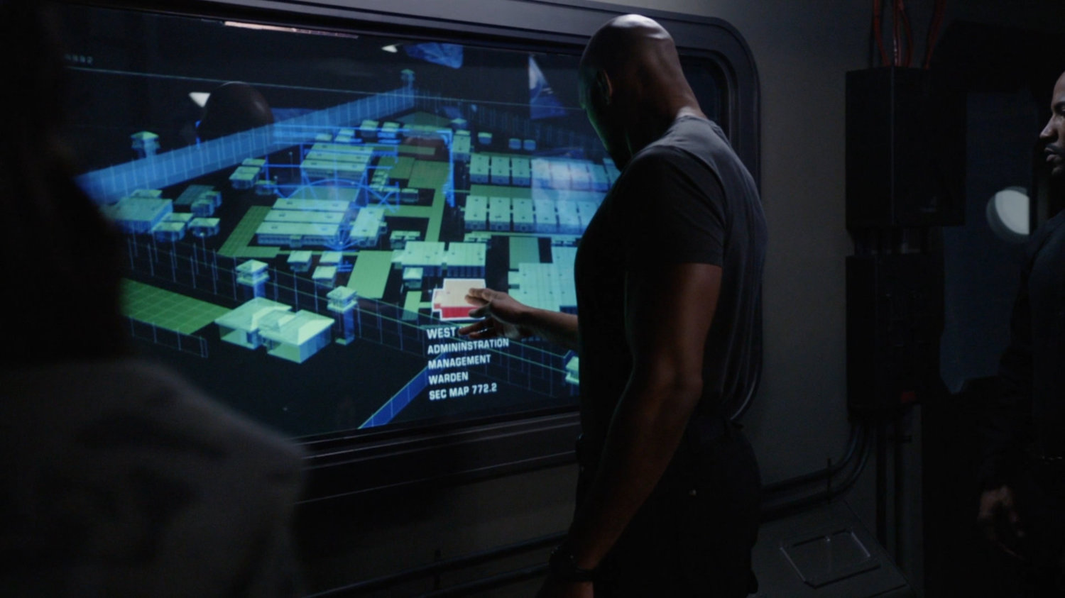 Mack pointing to a graphical map of South Ridge Penitentiary.