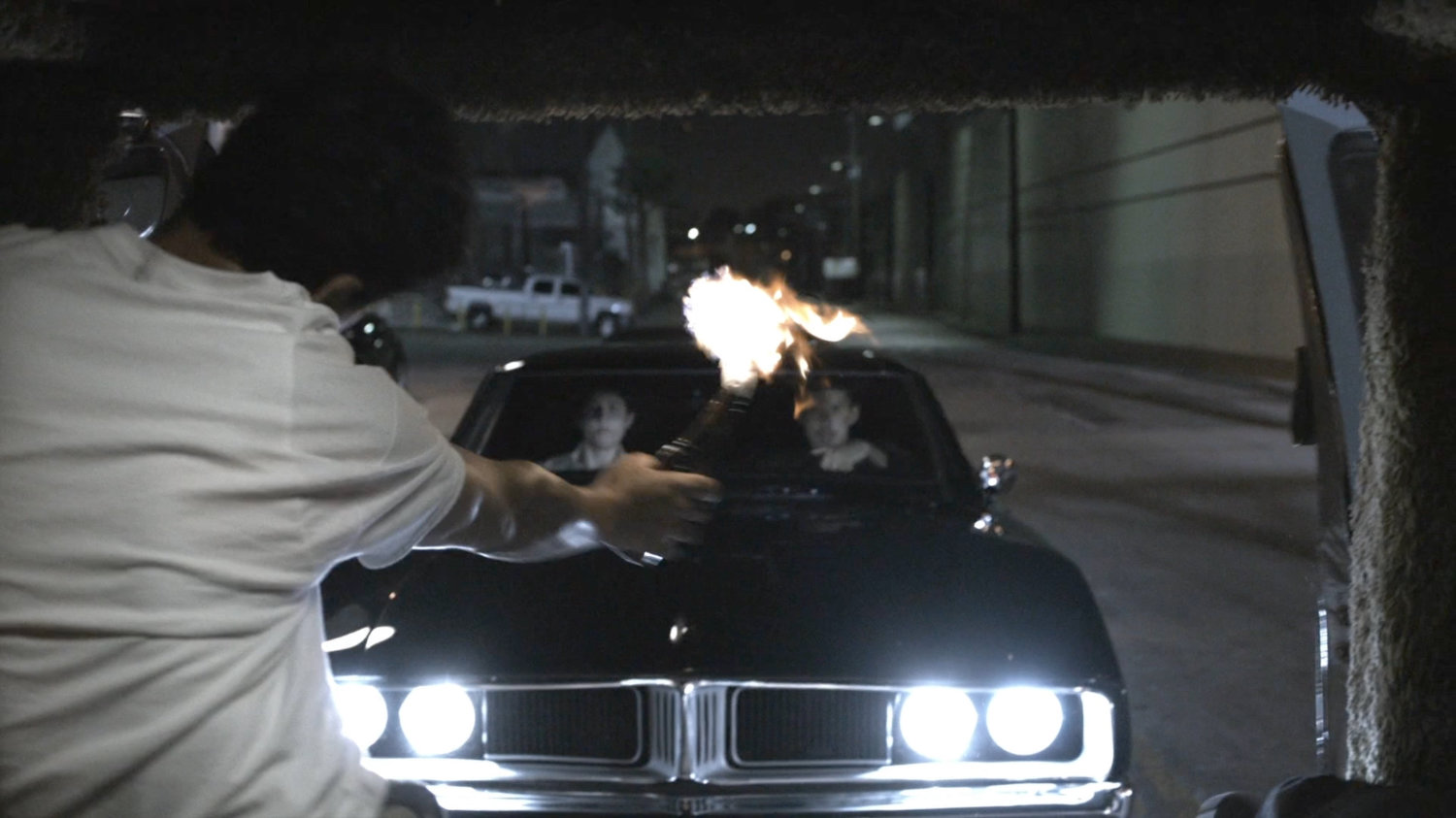 Man throwing Molotov cocktail at black Charger.