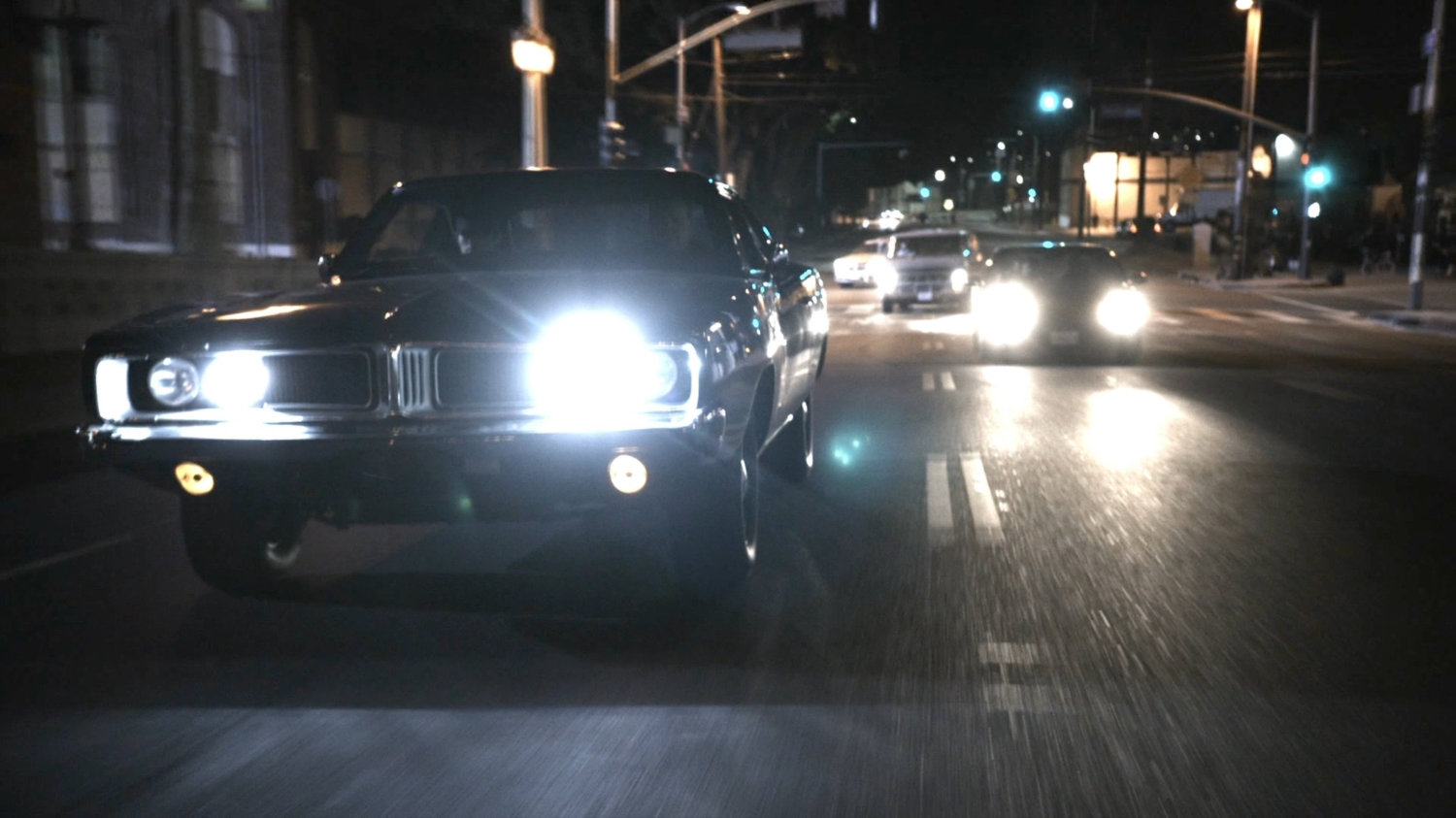 Black Charger being pursued by van and car over bridge.