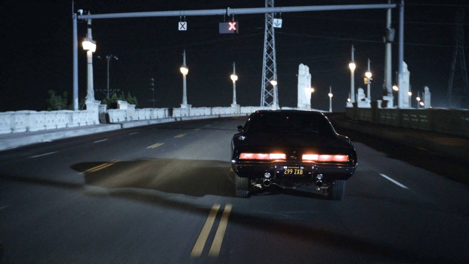 Black Charger driving over Los Angeles bridge.