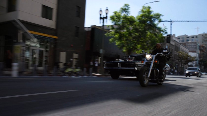 Mack on his motorcycle and black Charger on a street in Los Angeles.