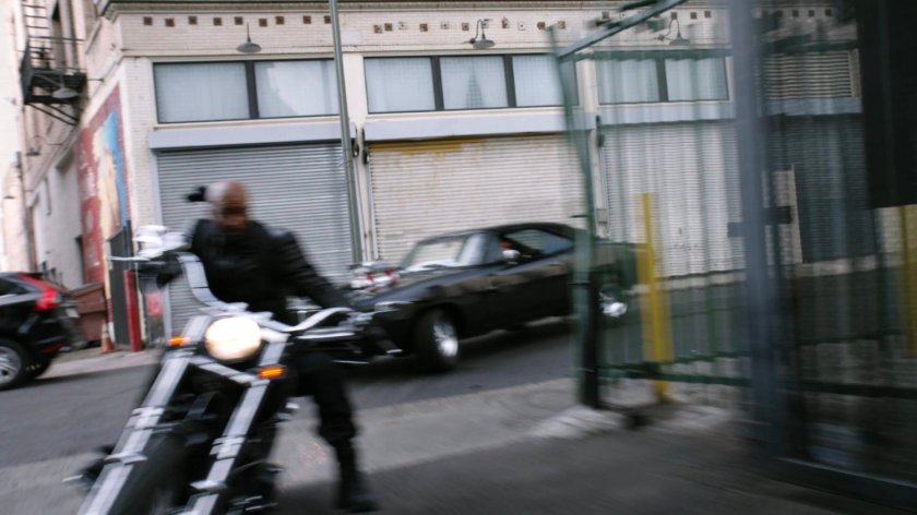 Mack on his motorcycle and black Charger taking a corner into an alley in Los Angeles.
