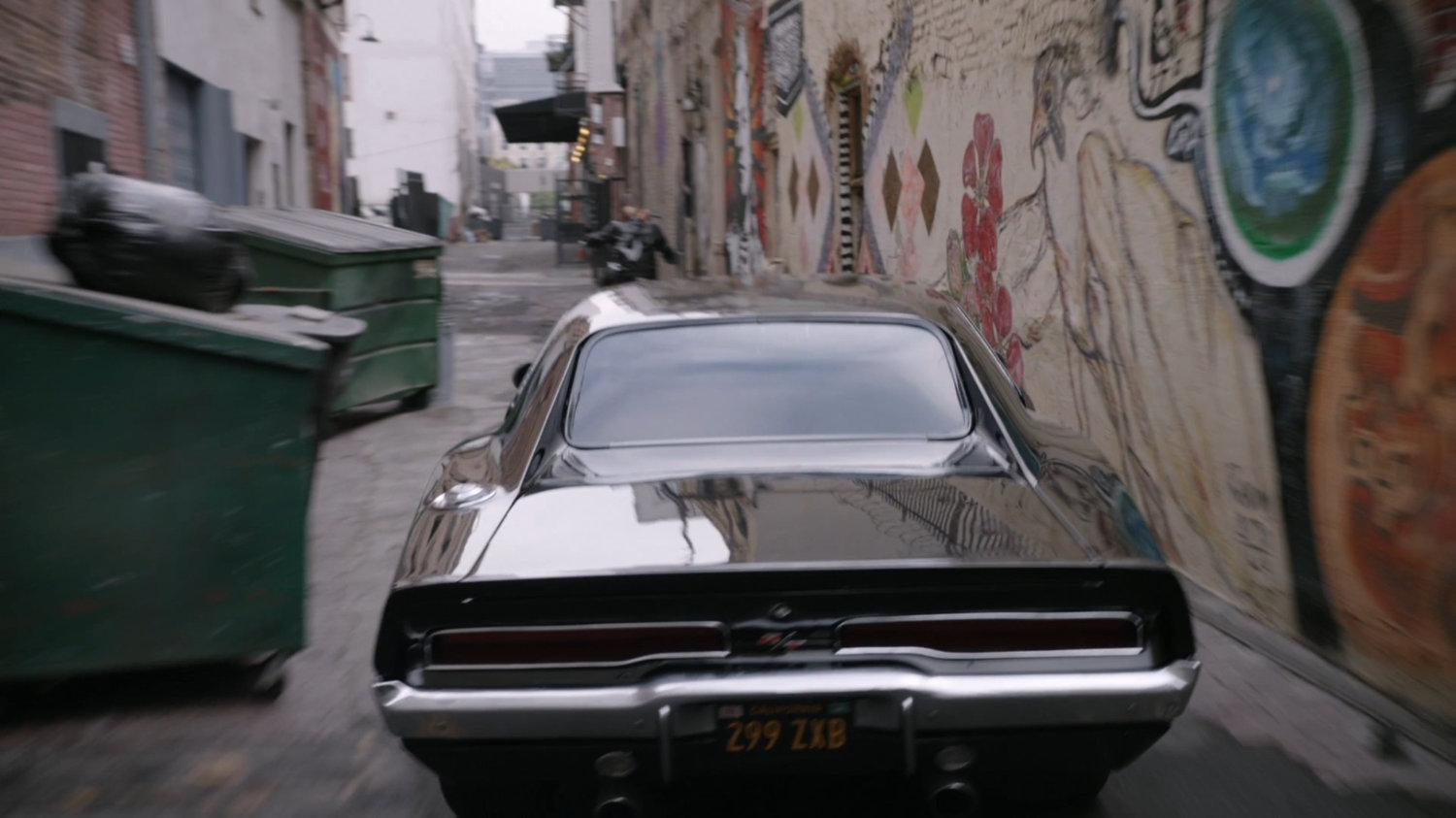 Mack on his motorcycle and black Charger in an alley in Los Angeles.