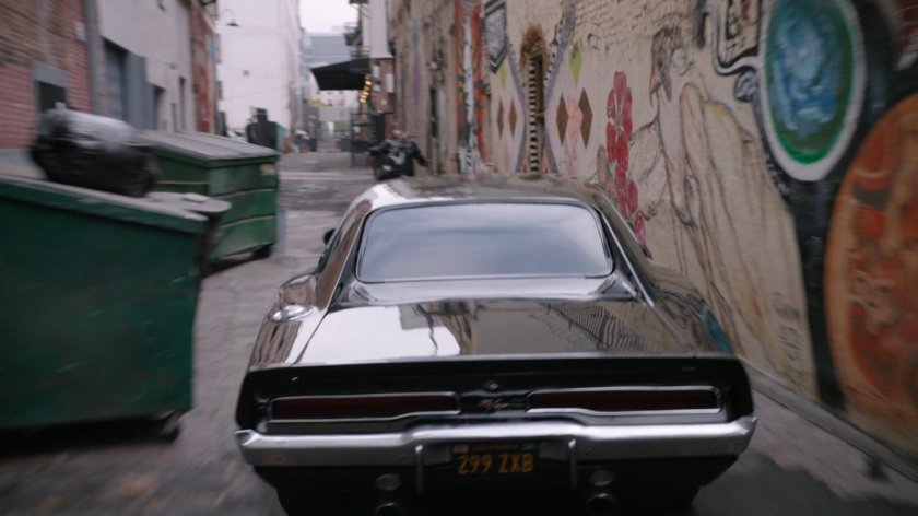 Mack on his motorcycle and black Charger in an alley in Los Angeles.