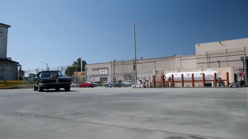 Black Charger driving through Chinatown Crew Warehouse parking lot.