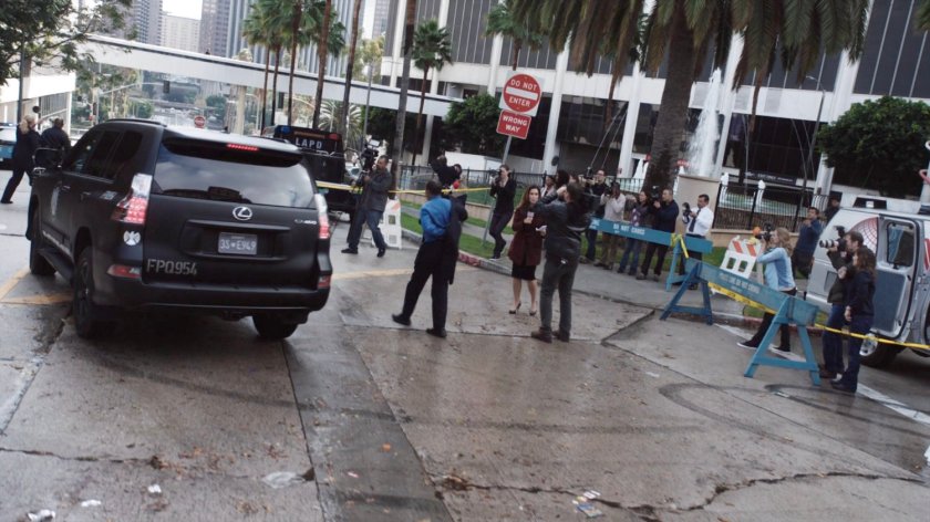 A police barricade with onlookers and reporters gathered around.