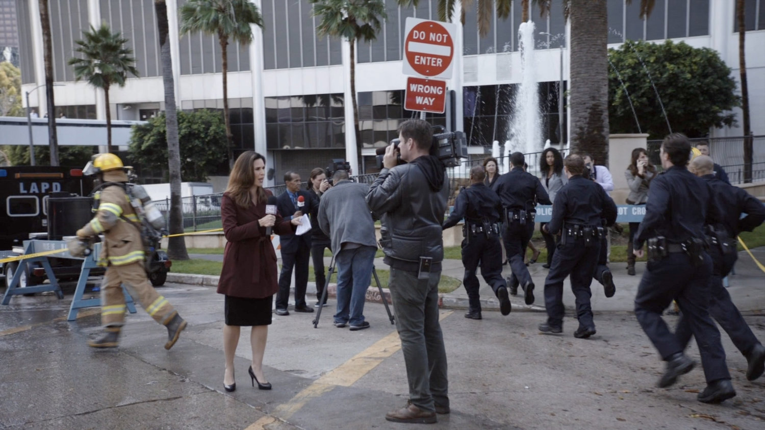A police barricade with onlookers and reporters gathered around.