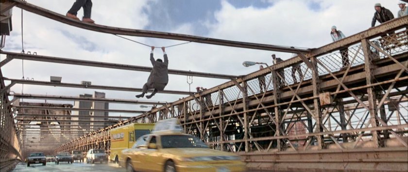 Man hanging from girder above traffic on Brooklyn Bridge.